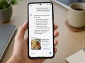 Een hand die een smartphone vasthoudt waarop een AI-antwoord te zien is, met daaronder een gesponsorde advertentie