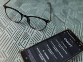 Een smartphone waarop de ChatGPT-app is geopend, naast een bril op een oppervlak met een patroon