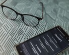 Een smartphone waarop de ChatGPT-app is geopend, naast een bril op een oppervlak met een patroon