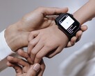De hand van een volwassene die een smartwatch om de pols van een kind omdoet