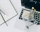 Miniatuurwinkelwagentje op het toetsenbord van een laptop, met ‘Nu winkelen’ op het scherm