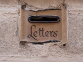 Een stenen brievenbus met het woord „Letters“ in een muur uitgehouwen