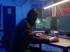 Generieke hacker op een werkstation met twee monitoren die een aanval op de toeleveringsketen uitvoert.
