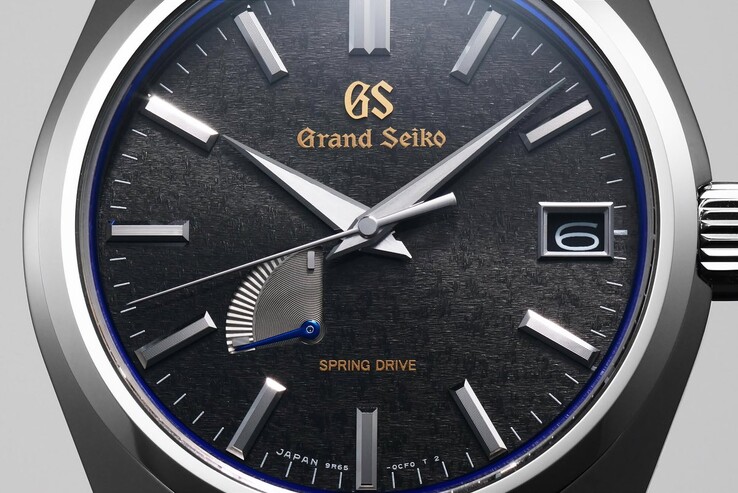 Close-up van de Grand Seiko SBGA531 met zijn grijze wijzerplaat met structuur, gefacetteerde uurmarkeringen, goudkleurig GS-logo en blauwe gangreservewijzer.