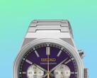 Close-up van de bovenste helft van de Seiko HGK003, waarbij de nadruk ligt op de hoekige roestvrijstalen kast, de bovenste schakels van de armband, de bovenste drukknoppen en het bovenste gedeelte van de paarse wijzerplaat tegen een levendige groene en blauwe achtergrond met kleurverloop.