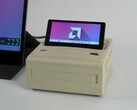 Een Ayaneo AM01S mini PC in retro-stijl met beige afwerking, voorzien van een ingebouwd opklapbaar secundair scherm waarop het Windows-bureaublad te zien is. (ETA Prime via YouTube)