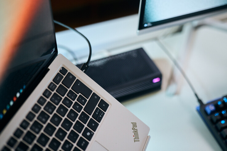 Macro-opname van een Thunderbolt 5-kabel die is aangesloten op de poort aan de zijkant van een Lenovo ThinkPad X9-laptop, met de Aorus eGPU op de achtergrond.