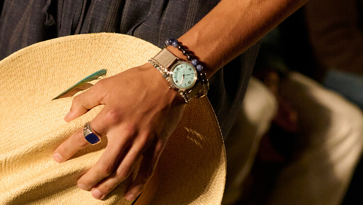 Een persoon die het aquablauwe Timex x Todd Snyder Marlin Mesh-horloge met een roestvrijstalen armband draagt.