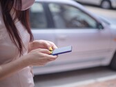 Een vrouw die op haar smartphone typt met een zilveren auto op de achtergrond