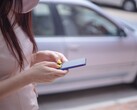 Een vrouw die op haar smartphone typt met een zilveren auto op de achtergrond