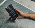 Hand die een smartphone vasthoudt met de ChatGPT-app geopend boven een tafel met een patroon