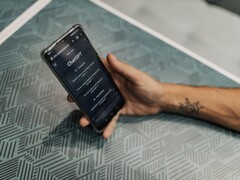 Hand die een smartphone vasthoudt met de ChatGPT-app geopend boven een tafel met een patroon