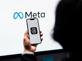 Een hand houdt een smartphone voor een groot Meta-logo