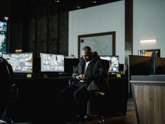 Een beveiligingsanalist in een controlekamer voor verschillende beeldschermen