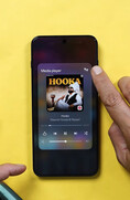 Een OnePlus-smartphone waarop de mediaspeler-widget wordt weergegeven, terwijl een gebruiker op het pictogram voor audio-uitvoer tikt om de bedieningselementen voor het delen van audio via Bluetooth te openen.
