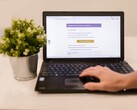 Een laptop op een bureau waarop een geopende e-mailinbox te zien is, met daarnaast een potplant.
