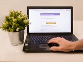 Een laptop op een bureau waarop een geopende e-mailinbox te zien is, met daarnaast een potplant.