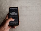 Hand die een smartphone vasthoudt waarop de ChatGPT-interface te zien is, boven een grijs stenen oppervlak
