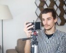Een jonge man filmt zichzelf thuis met een smartphone die op een statief is bevestigd
