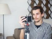 Een jonge man filmt zichzelf thuis met een smartphone die op een statief is bevestigd
