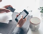 Een persoon die op een smartphone tikt terwijl hij of zij in de andere hand een bankkaart vasthoudt