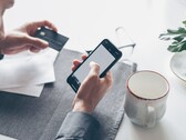 Een persoon die op een smartphone tikt terwijl hij of zij in de andere hand een bankkaart vasthoudt