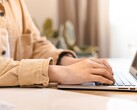 Handen die op het toetsenbord van een open laptop typen op een helder verlicht bureau