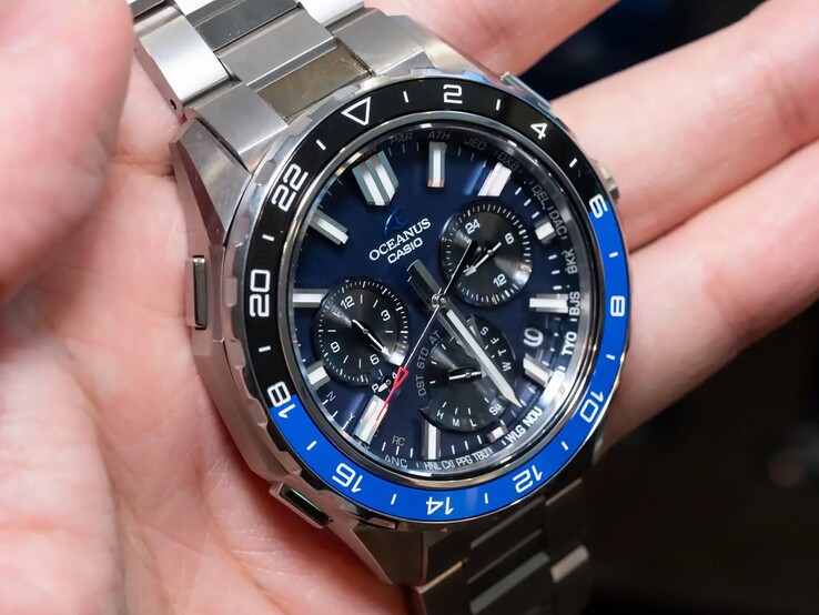 Close-up van de Casio Oceanus OCW-P3000 met blauwe wijzerplaat, waarop stadscodes, subwijzerplaten, lichtgevende uurmarkeringen en brede wijzers te zien zijn.