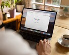 Persoon achter een laptop met de Google-startpagina geopend, naast een kop koffie