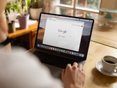 Persoon achter een laptop met de Google-startpagina geopend, naast een kop koffie