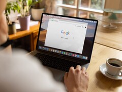 Persoon achter een laptop met de Google-startpagina geopend, naast een kop koffie