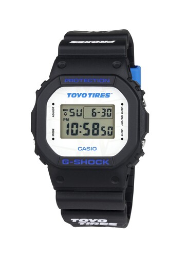 De witte wijzerplaat is prominent voorzien van het Toyo Tires-logo, terwijl blauwe letters contrasteren met het klassieke vierkante G-Shock ontwerp.