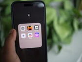 Hand die een smartphone vasthoudt met een map vol AI-apps op het scherm