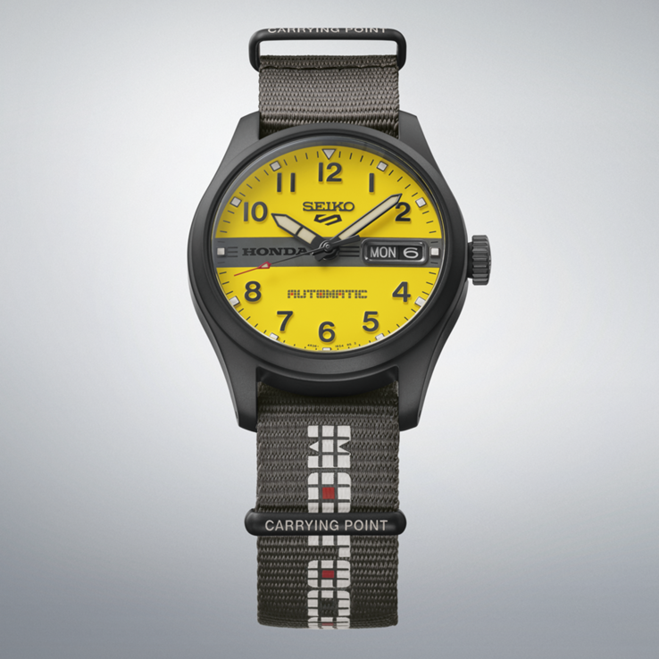 Vooraanzicht van de Seiko 5 Sports Field x Honda Motocompo Limited Edition met een gele wijzerplaat, een zwart Honda-logo in het midden en een grijze nylon band.