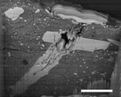 Een beeld van een elektronenmicroscoop van een inslagkrater van een micrometeoriet in een deeltje van asteroïde Bennu-materiaal (Afbeeldingsbron: NASA, en Zia Rahman)