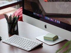 Een iMac op een bureau, met het macOS-dock zichtbaar op het scherm en een Apple-toetsenbord ervoor