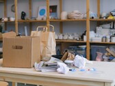 Kartonnen doos en papieren zakken op een houten tafel in een kantoor met rekken