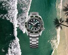 Seiko Prospex HBC001 duikershorloge met groene wijzerplaat en lunette op een achtergrond van strand en oceaan in de lucht.
