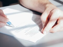 Een hand ondertekent een document met een blauwe balpen