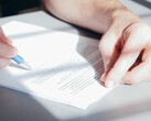 Een hand ondertekent een document met een blauwe balpen