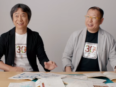 Een screengrab van Shigru Miyamoto en Tezuka Takashi in t-shirts ter ere van de 30e verjaardag van Super Mario Bros