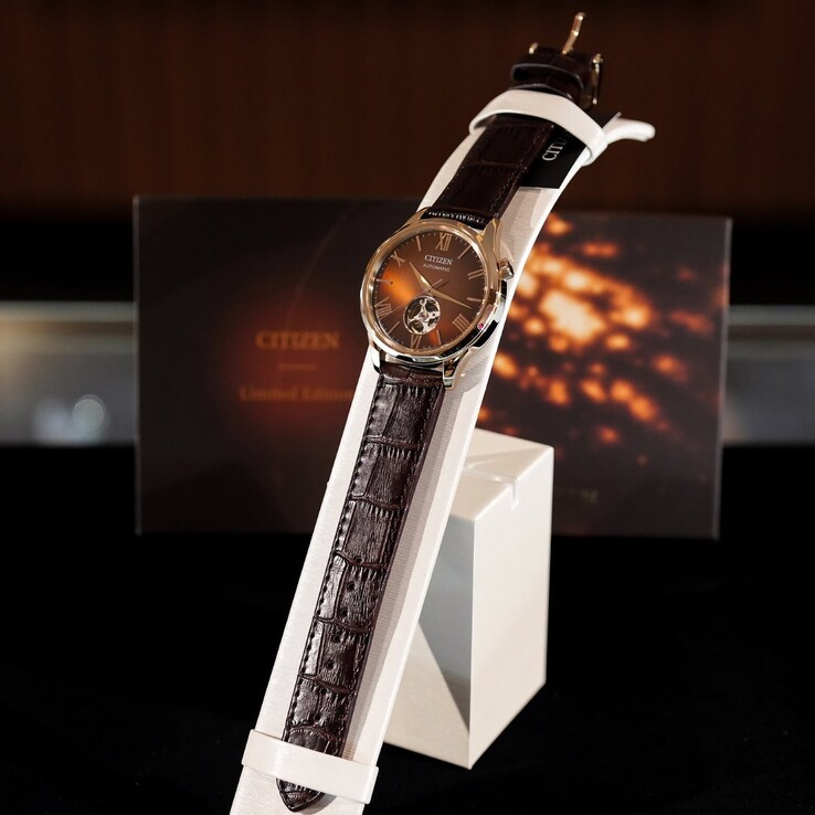 Het Citizen-horloge is gemonteerd op een witte, gebogen displaystandaard. De afbeelding toont de donkerbruine leren band met krokodillenreliëf in zijn volledige lengte en de reflecterende bruine wijzerplaat,