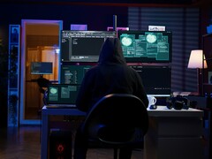 Figuur met capuchon bij een opstelling met meerdere schermen die een cyberaanval uitvoeren.