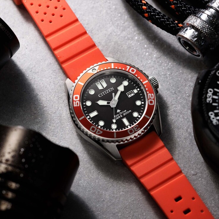 Citizen Promaster Marine BN0268-01E duikhorloge met een zwarte wijzerplaat, oranje lunette en oranje band, gefotografeerd op een gestructureerd oppervlak.