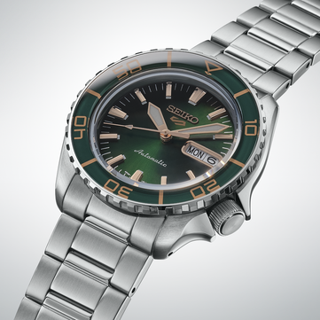 Close-up van de Seiko 5 Sports SKX HDB005, met de nadruk op de donkergroene wijzerplaat, roségoudkleurige wijzers en opgelegde indexen, en de bijpassende groene lunette met goudkleurige markeringen.