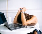 Vrouw die naar haar smartphone kijkt, met een laptop naast haar