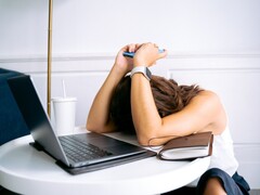 Vrouw die naar haar smartphone kijkt, met een laptop naast haar