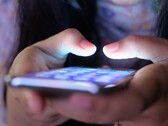 Twee handen houden een smartphone met een oplichtend scherm vast in het schemerlicht
