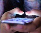 Twee handen houden een smartphone met een oplichtend scherm vast in het schemerlicht