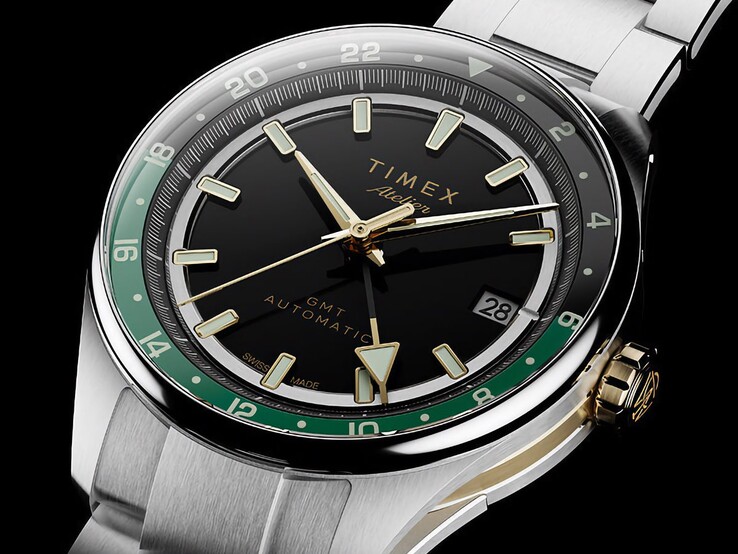 Schuin aanzicht van de Timex Atelier GMT Première M1a met de zwarte wijzerplaat, groene GMT-ring, goudkleurige kroon en roestvrijstalen horlogeband.